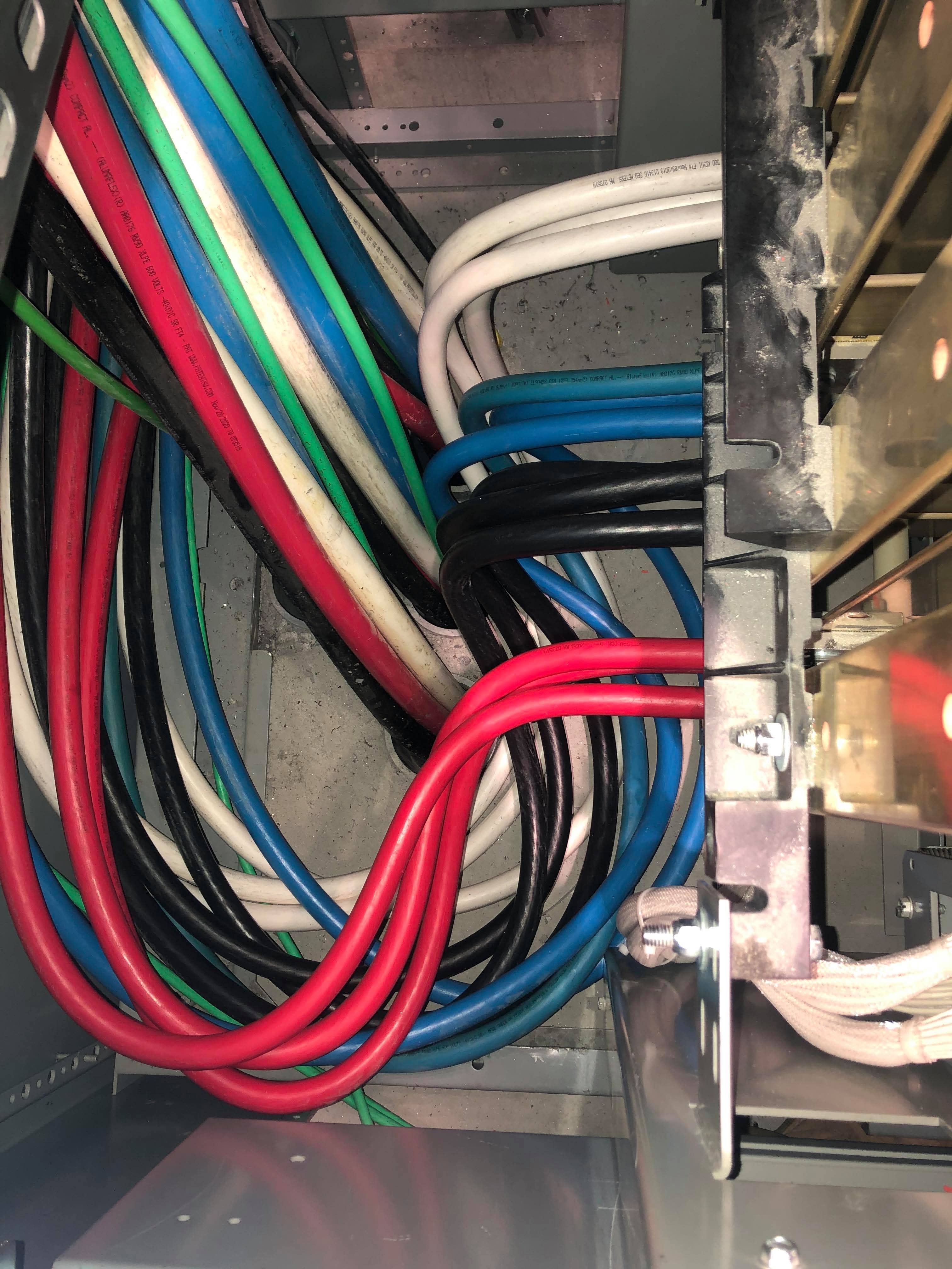 Bundled feeder cables with red, blue, black, and white conductors routed neatly inside a cabinet