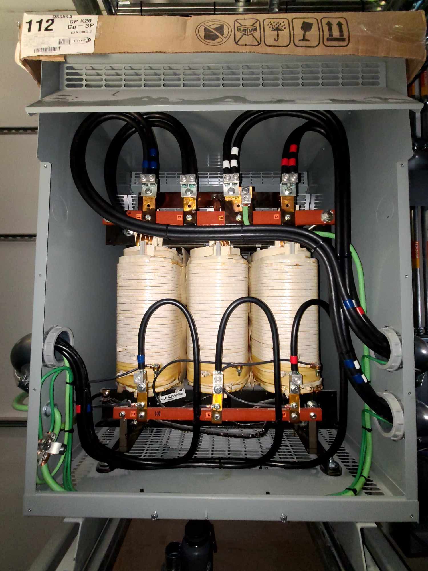 Three-phase transformer with neat black feeder loops inside an enclosure